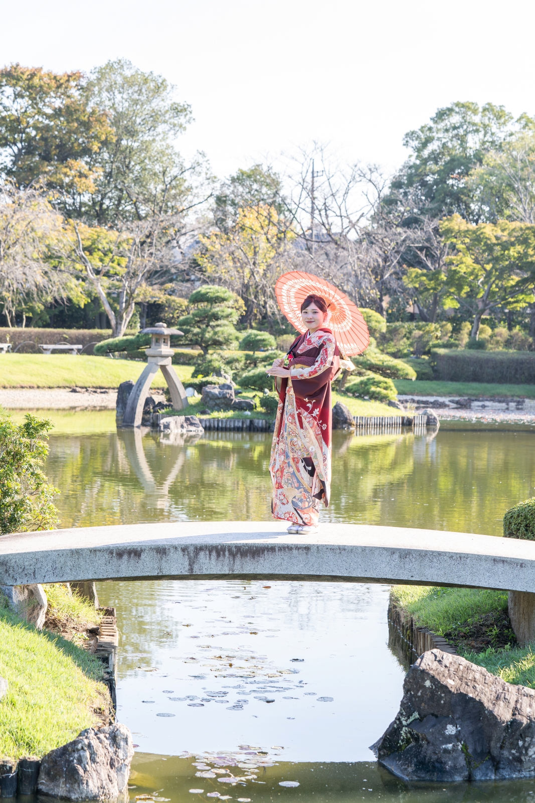 日本庭園・花田苑和傘と美しい振袖姿の女性。晴れの日、成人式撮影のロケーション風景